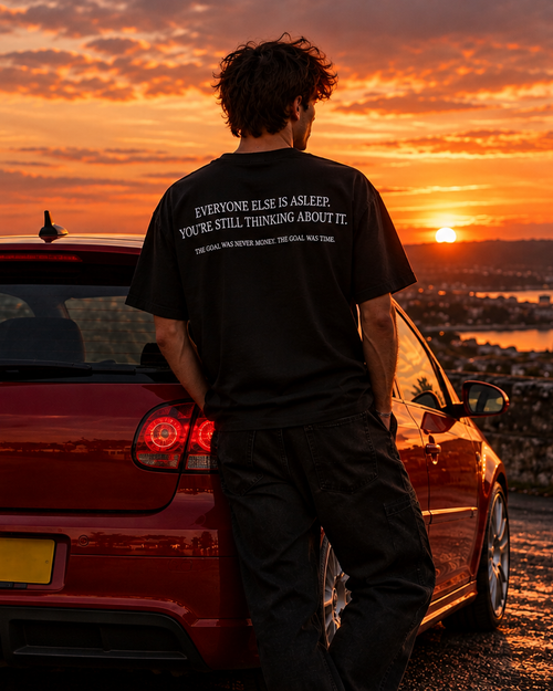 Back of the black UNSETTLED Core Tee on a model, printed in white: Everyone else is asleep. You’re still thinking about it.