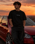 Front of the black UNSETTLED Core Tee on a model at sunset, with a small white UNSETTLED. print on the chest